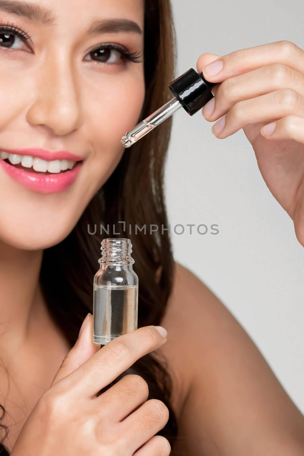 Closeup portrait of young ardent woman with healthy fresh skin taking cbd oil and dropper. Combination of beauty and cannabis for healthy skincare concept.