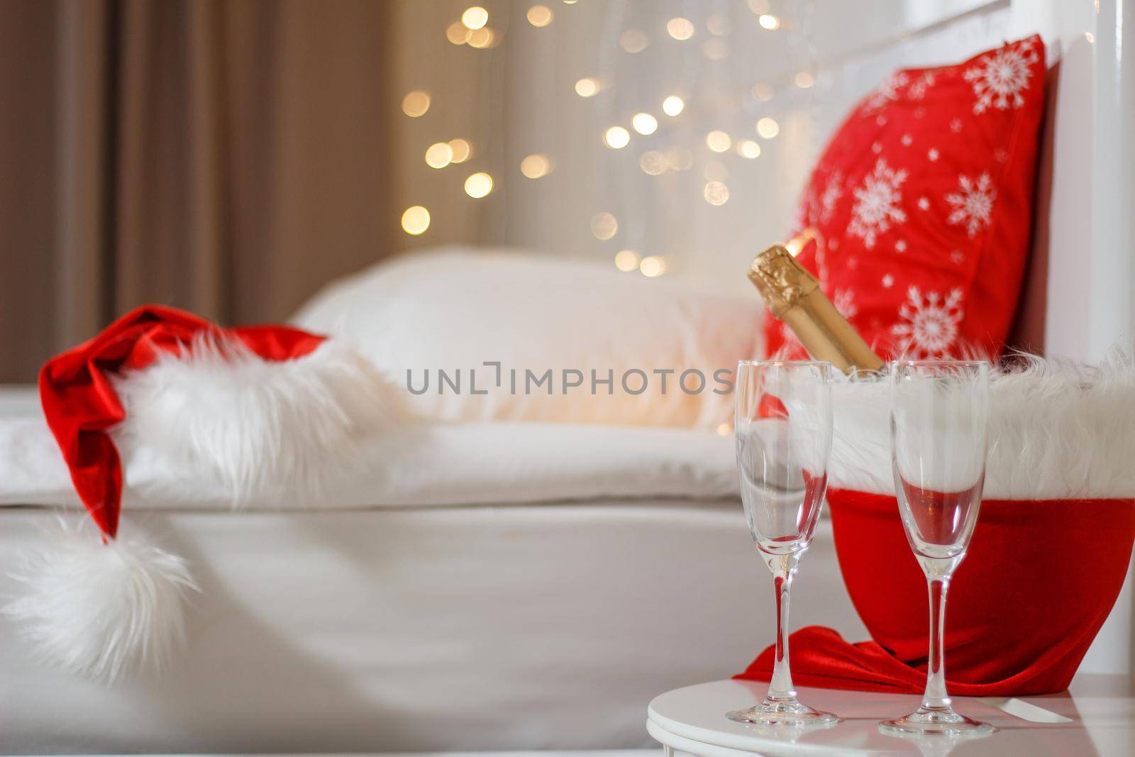 Two glasses and a bottle of champagne in a hotel room with Christmas decor. The concept of celebrating the new year in travel and hotel.