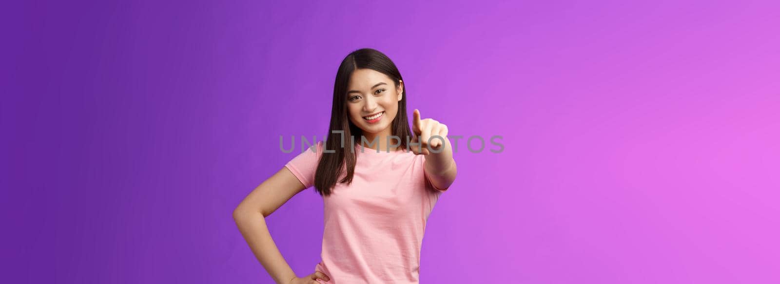 We need you our team. Friendly good-looking outgoing asian woman brunette pointing camera, indicate index finger, smiling motivated, picking person, making decision, stand purple background.