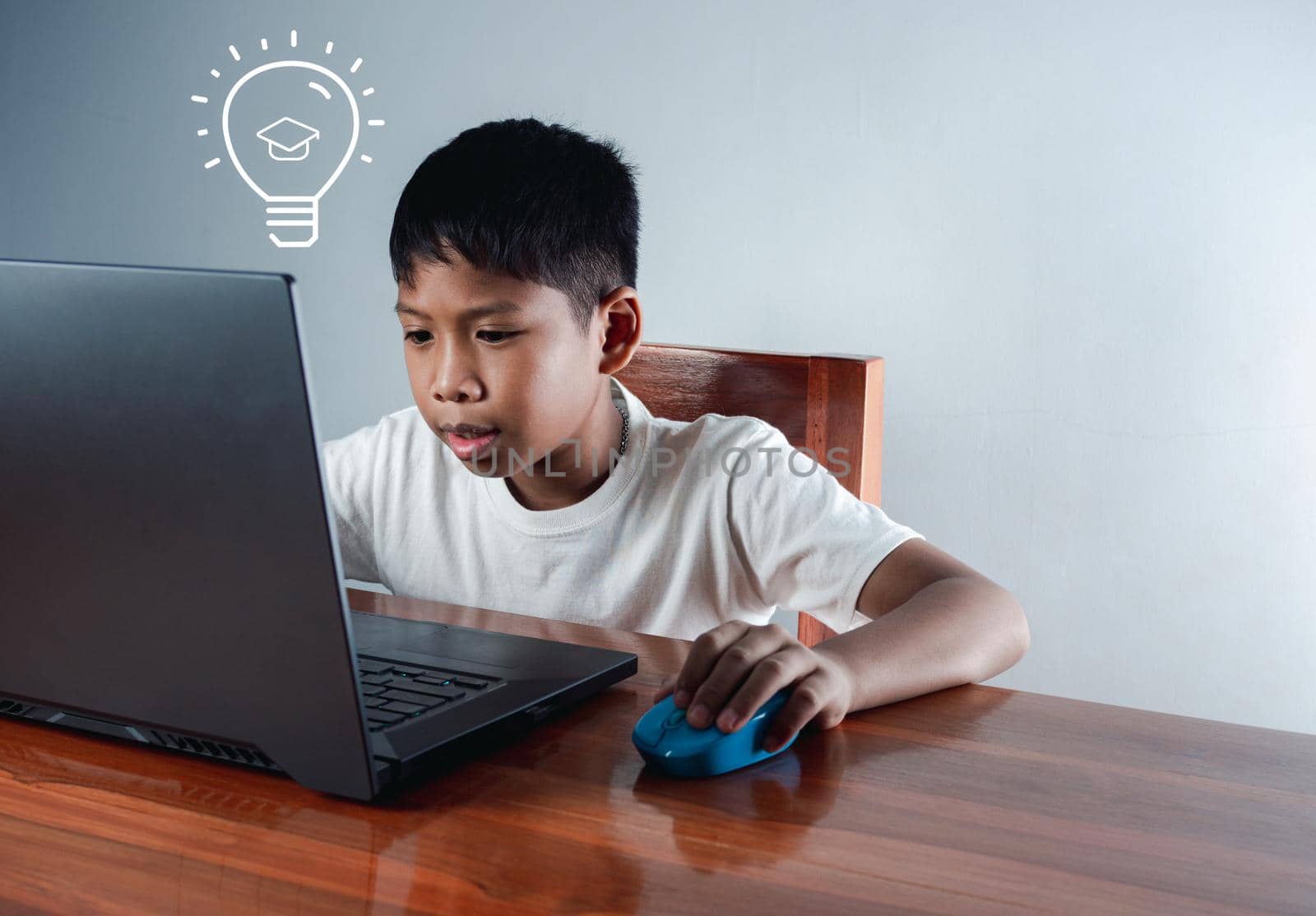Education concept image. Creative idea and innovation. boy sitting staring at computer and there is a light bulb icon next to it. by Unimages2527