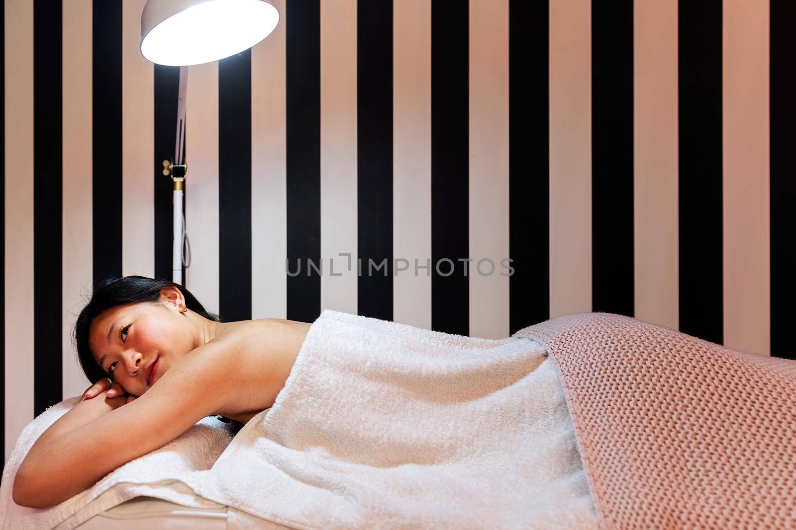 young woman relaxes lying on the couch before a relaxing massage in the beauty salon, concept of body care and wellness