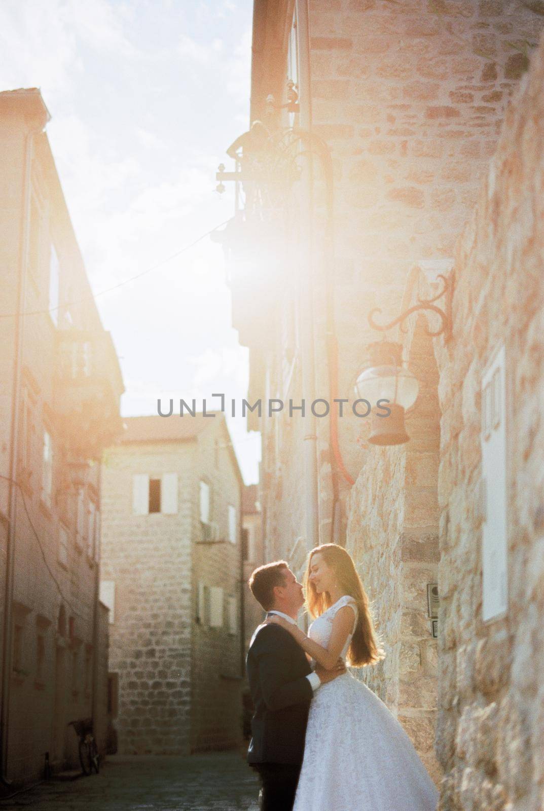 Groom lifted bride by the waist near the old stone house. High quality photo