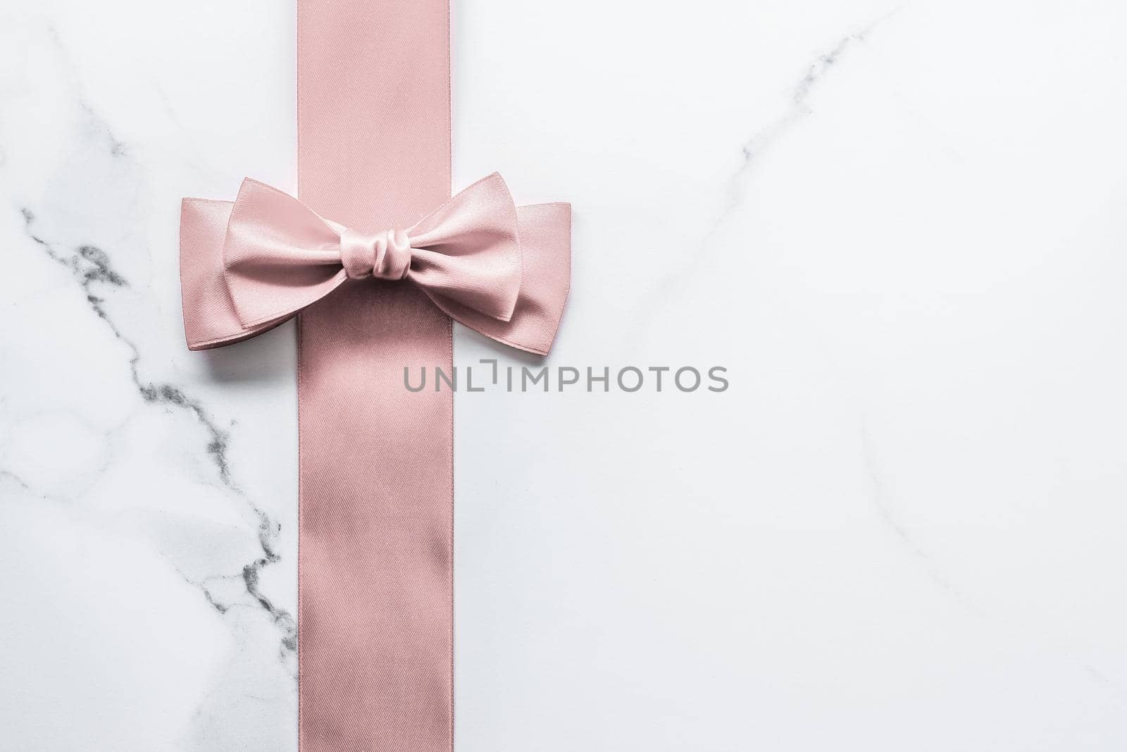 Birthday, wedding and girly branding concept - Beige silk ribbon and bow on marble background, glamour present mockup and fashion gift decoration for luxury beauty brand holiday flatlay design