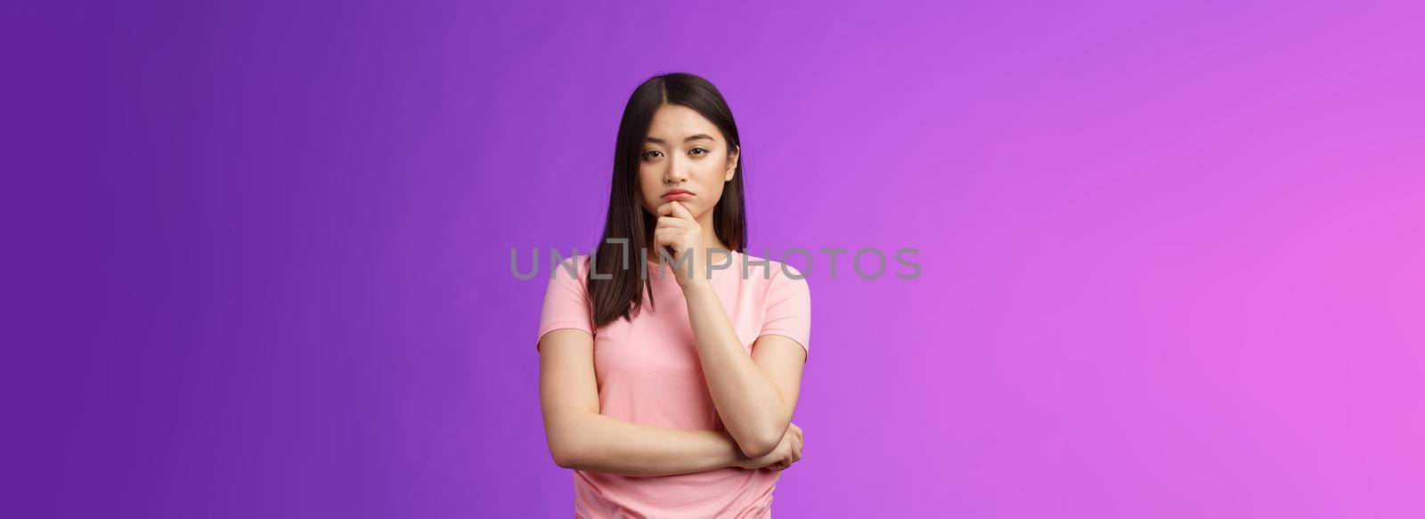 Judgemental serious-looking smart asian girl give expert look, touch chin thoughtful, squinting suspicious uncertain, make decision, choosing product, thinking, pondering plan, purple background.