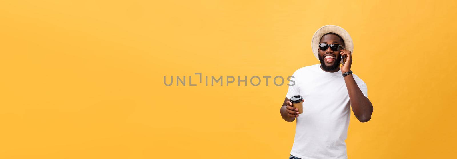 Handsome African American with mobile phone and take away coffee cup. Isolated over yellow gold background. by Benzoix