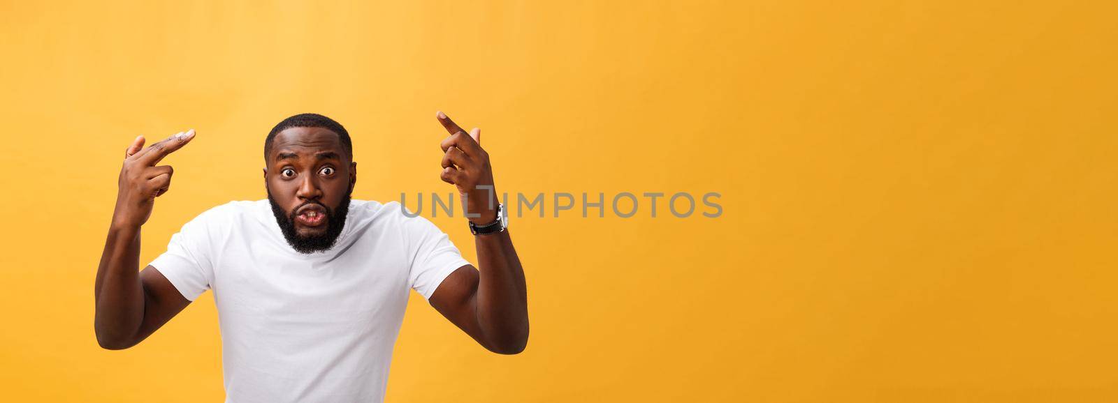 Portrait of african american man with hands raised in shock and disbelief. Isolated over yellow background