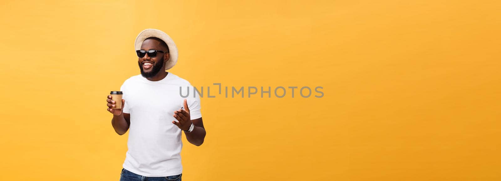 Stylish young african american man holding cup of take away coffee isolated over yellow background