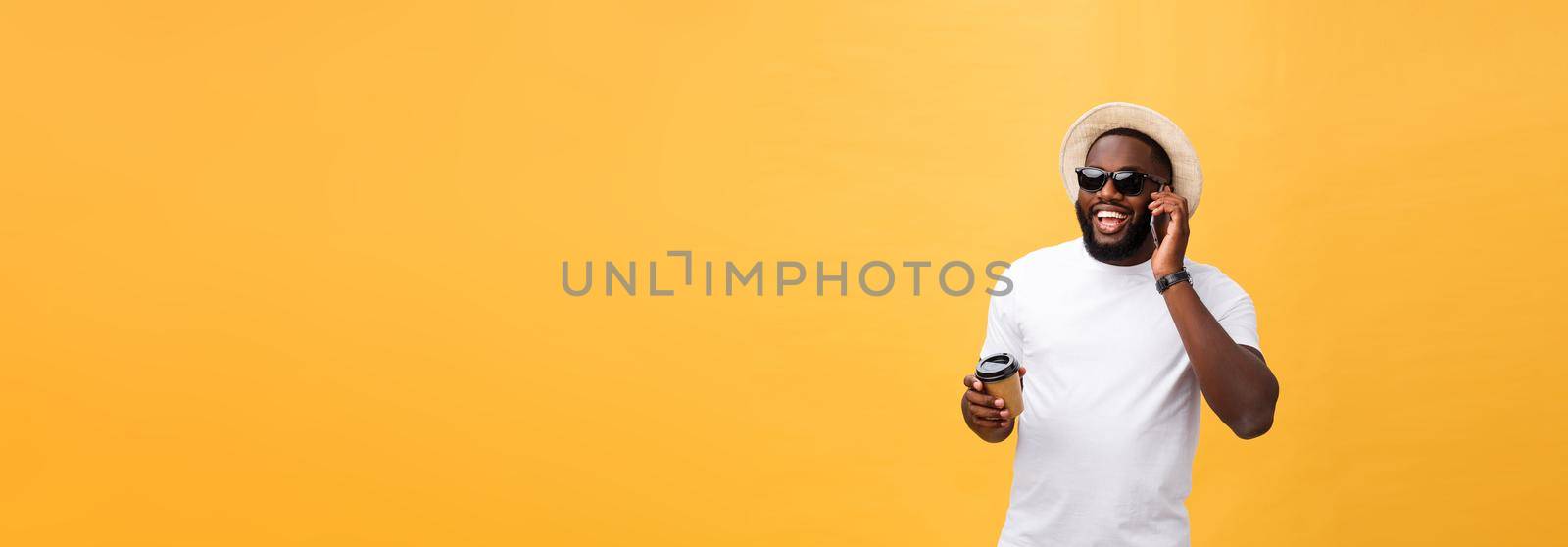 Handsome African American with mobile phone and take away coffee cup. Isolated over yellow gold background. by Benzoix
