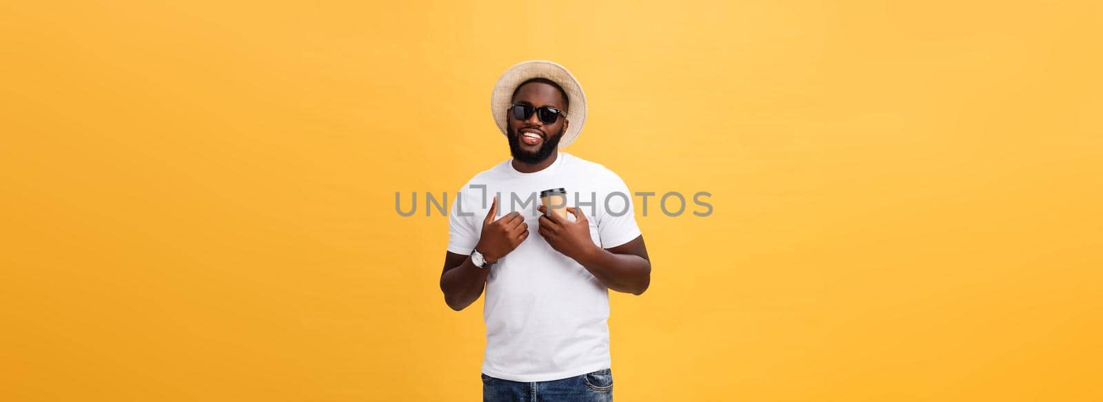 Stylish young african american man holding cup of take away coffee isolated over yellow background. by Benzoix