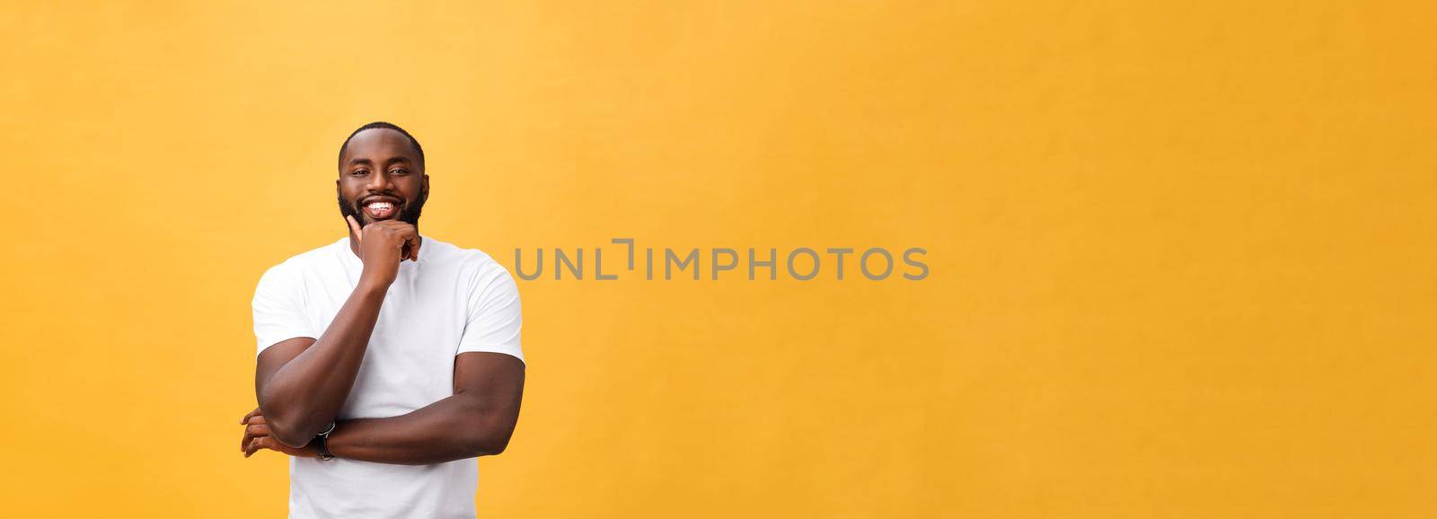 Portrait of a modern young black man smiling with arms crossed on isolated yellow background.