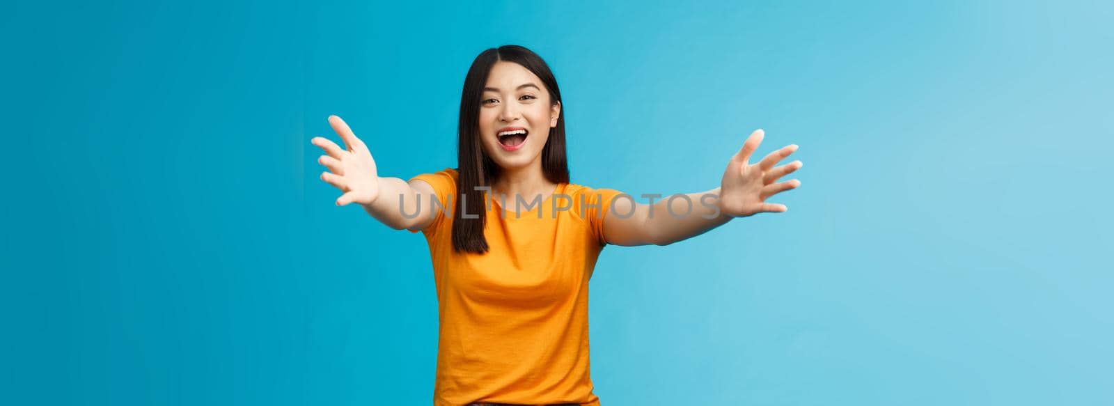 Come closer let me hug you. Cheerful lovely asian brunette girl stretch hands forward wanna cuddle, embracing friend smiling broadly inviting dear guests welcoming, stand blue background.