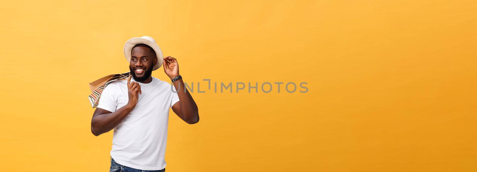 Happy african american man holding shopping bags on yellow background. Holidays concept by Benzoix
