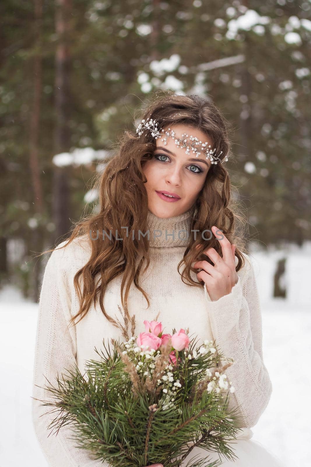 Beautiful bride in a white dress with a bouquet in a snow-covered winter forest. Portrait of the bride in nature.