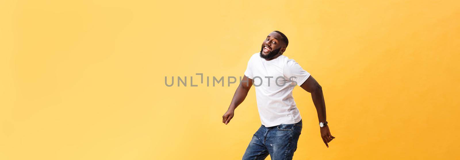 Full length of handsome young black man jumping against yellow background