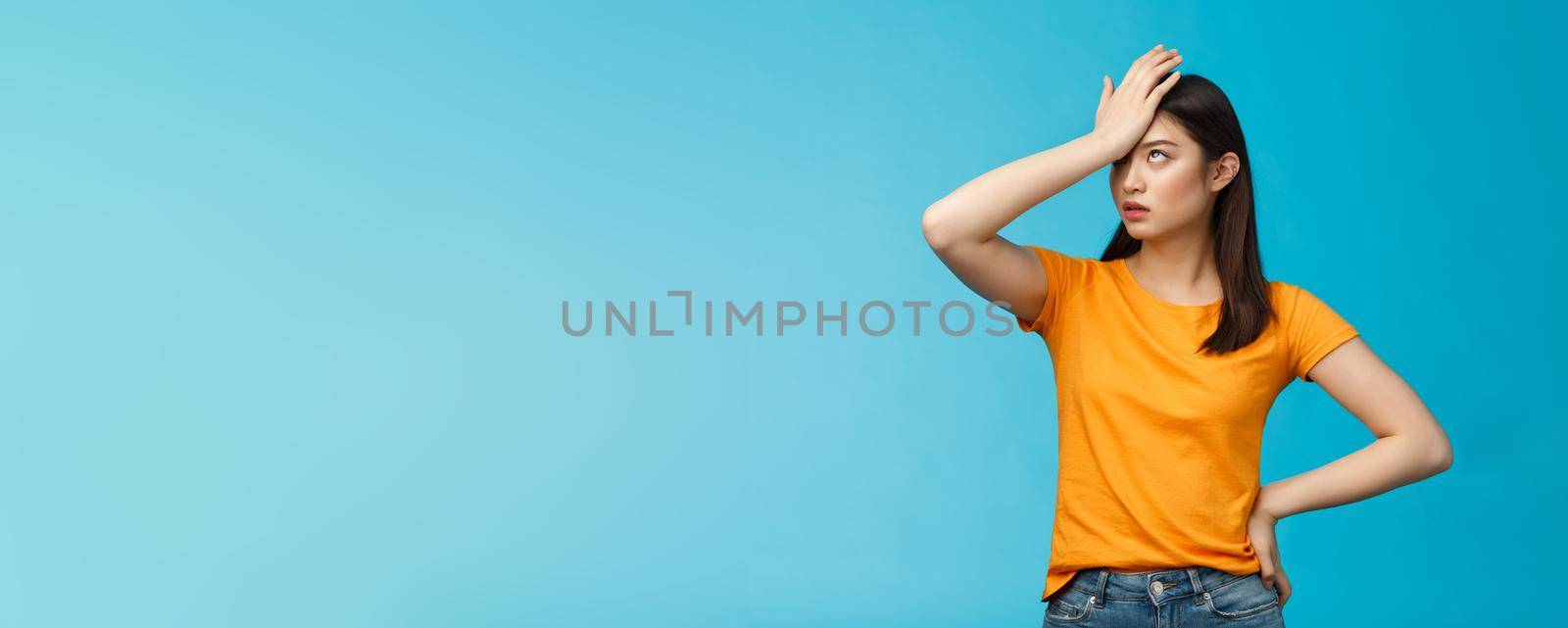 Annoyed arrogant asian girl punch forehead make facepalm sign, roll eyelids irritated pissed, cannot stand lame talks look disappointed ingorant, unwilling to listen, stand blue background by Benzoix