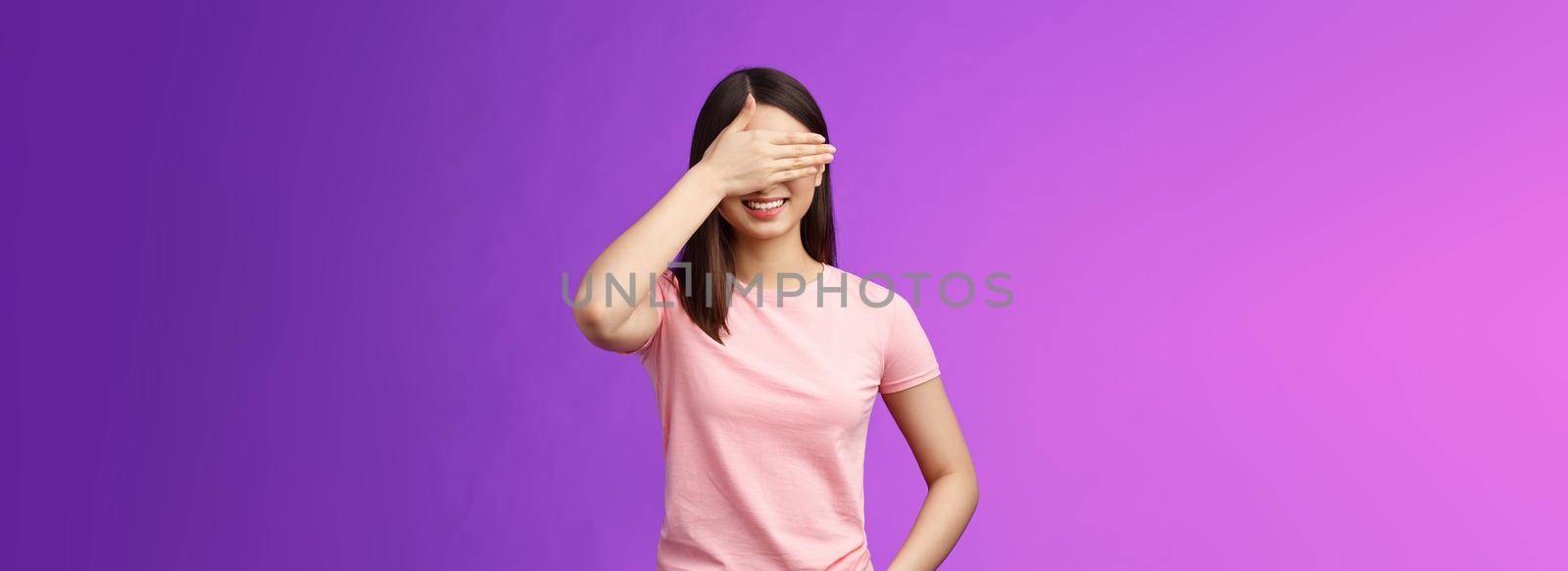 Cute tender stylish asian woman brunette smiling joyfully, anticipating gift, close eyes, cover face palm, awaiting present, cannot wait see what boyfriend prepared, stand purple background.