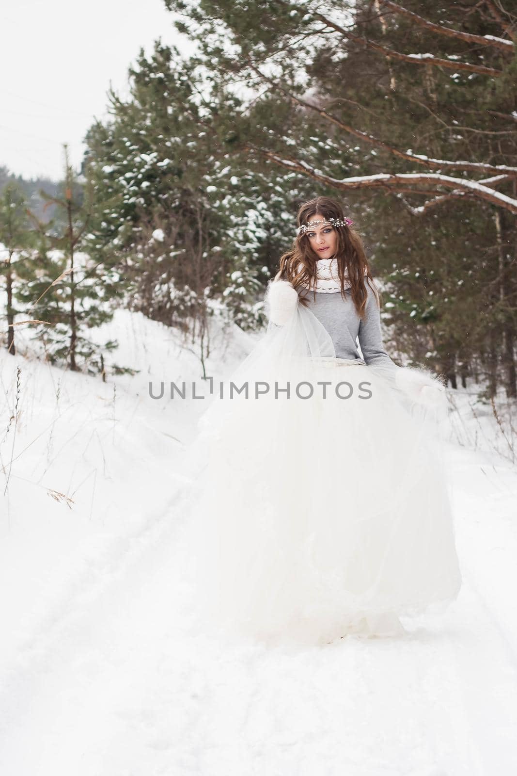 Beautiful bride in a white dress with a bouquet in a snow-covered winter forest. Portrait of the bride in nature by Annu1tochka