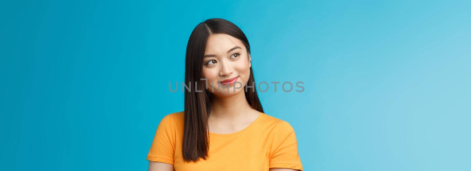 Close-up dreamy hopeful charming young asian woman wear yellow t-shirt turn sideways smiling delighted, contemplate beautiful summer scenery outside window sit office carefree, blue background.