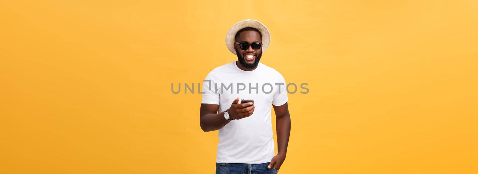 Cheerful African American man in white shirt using mobile phone application. happy dark skinned hipster guy read news from social network in mobile phone
