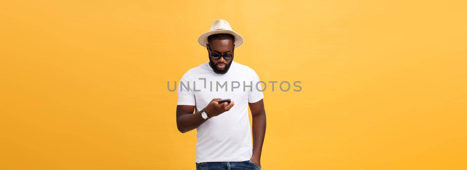 Cheerful African American man in white shirt using mobile phone application. happy dark skinned hipster guy read news from social network in mobile phone