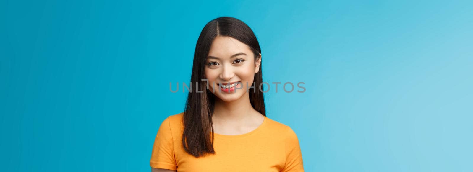 Close-up charming attractive asian girl pure clean skin condition, smiling joyfully look camera upbeat, politely listen, express positive good mood motivated achieve success, stand blue background.