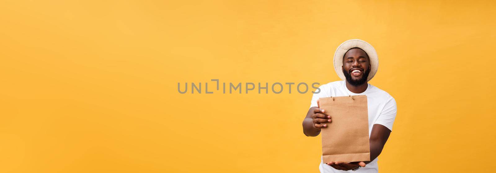 Happy african american man holding shopping bags on yellow background. Holidays concept.