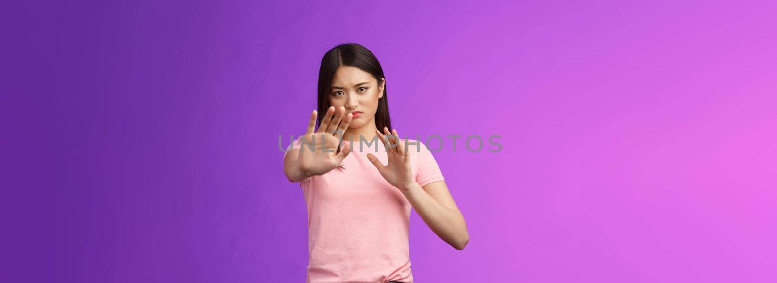 Displeased intense reluctant asian girl blocking, trying protect face, raise hands stop, prohibition gesture, frowning sulking, refusing bothering offer, stand purple background, rejecting.