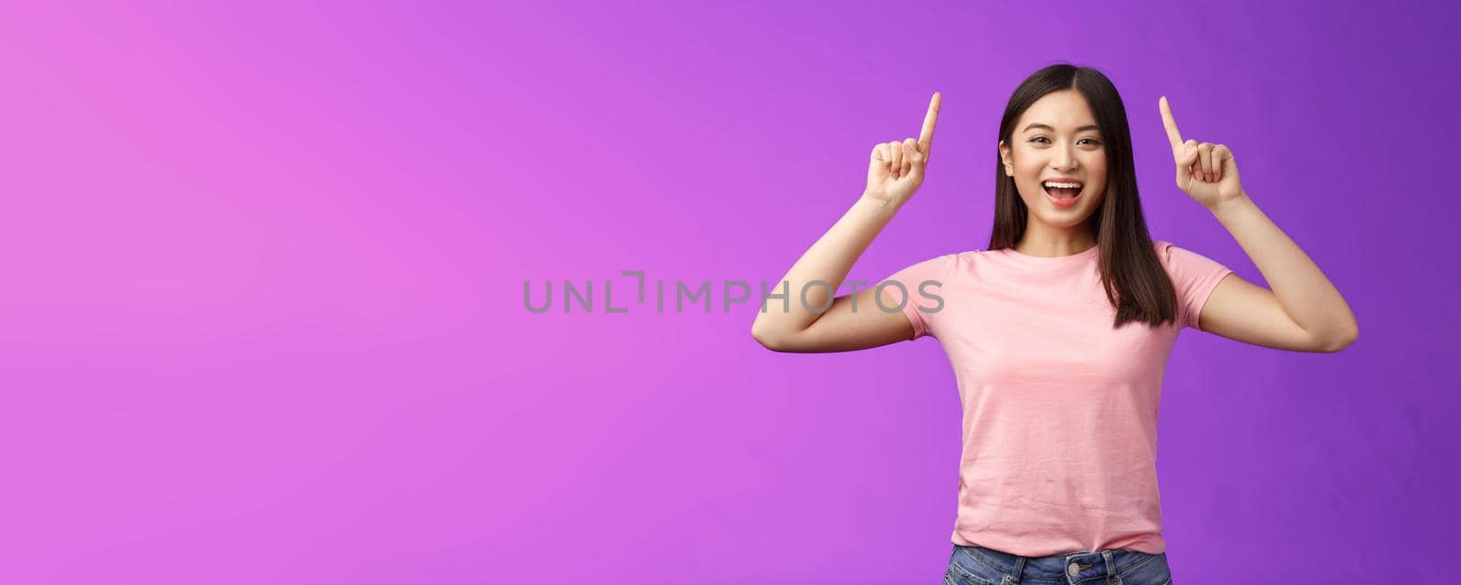 Charismatic good-looking lively smiling asian girl introduce product, pointing fingers up, indicate top advertisement, grinning toothy, excited telling good news, sharing link, purple background by Benzoix