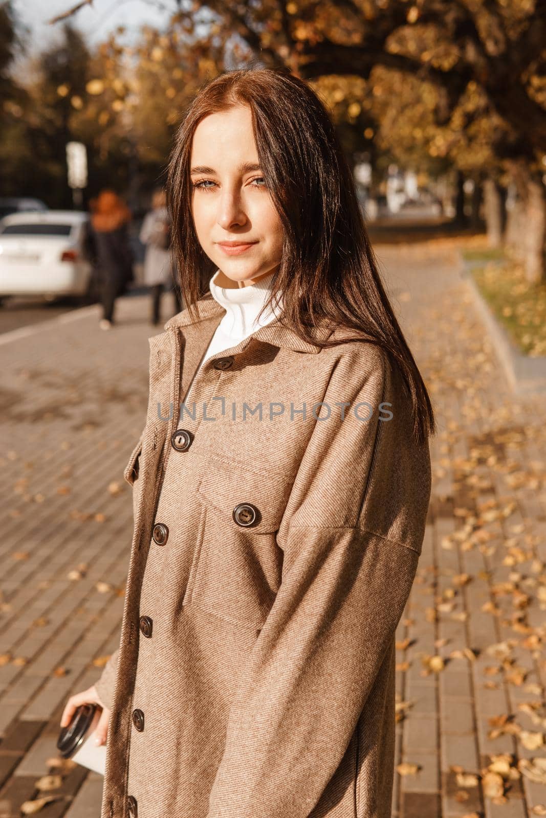 A stylish brunette woman walks around the autumn city. The season is autumn.