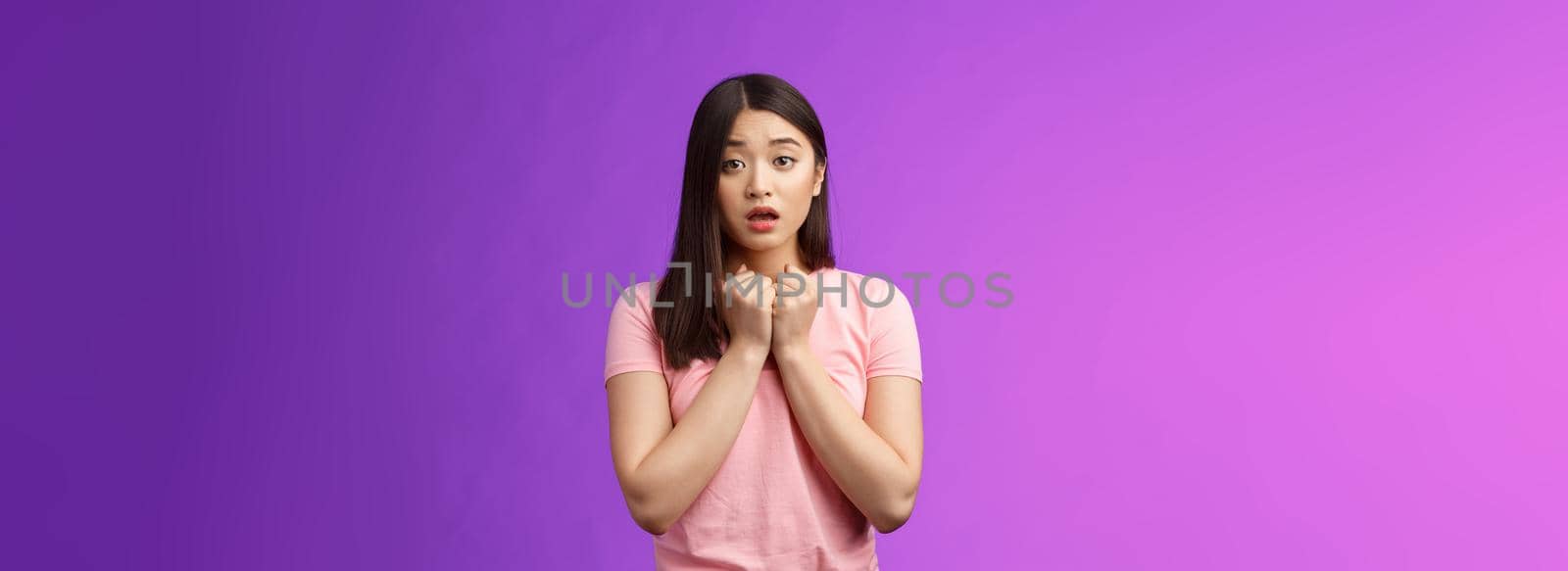 Timid concerned cute asian girl express empathy and worry, press hands heart upset, sorry for friend, open mouth, sighing sad nervous, hesitating, anxiously saying love you, stand purple background by Benzoix