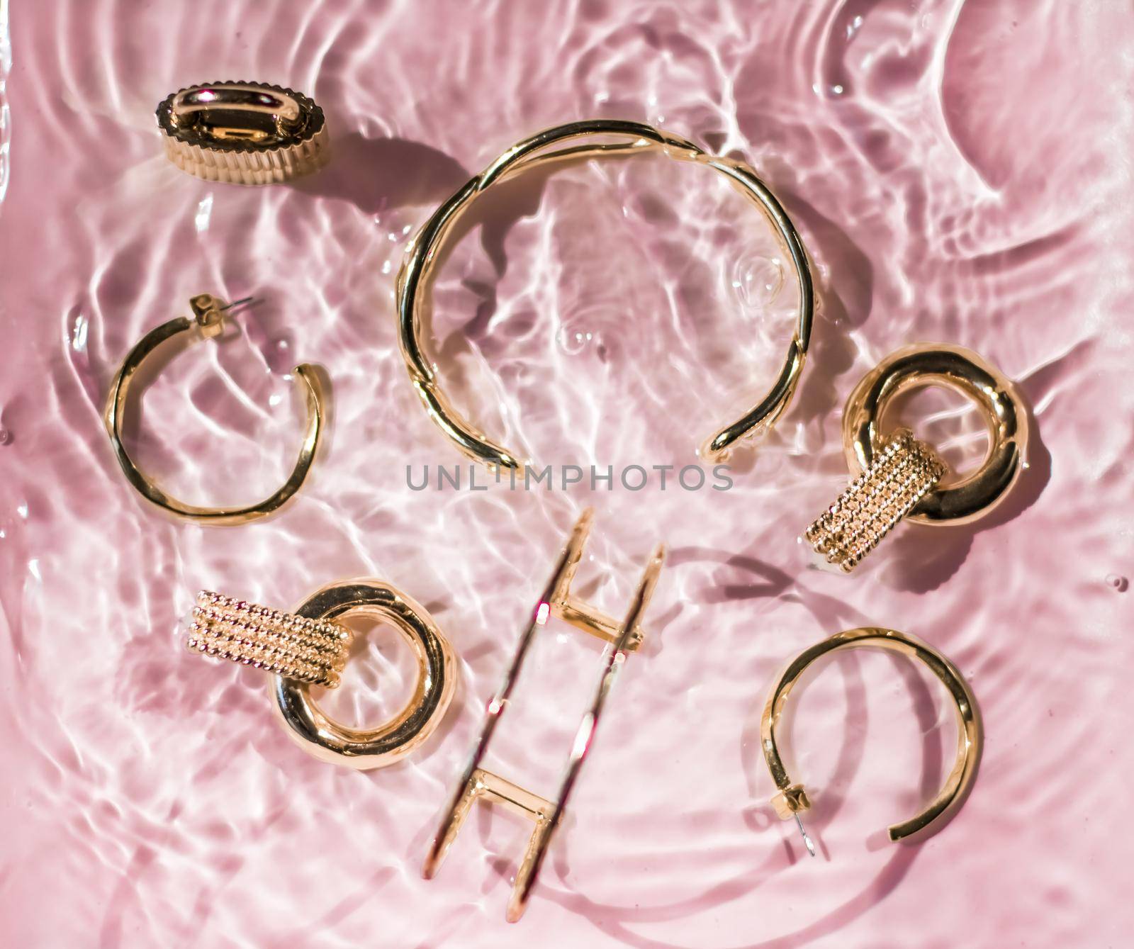 Jewellery branding, fashion gift and luxe shopping concept - Golden bracelets, earrings, rings, jewelery on pink water background, luxury glamour and holiday beauty design for jewelry brand ads