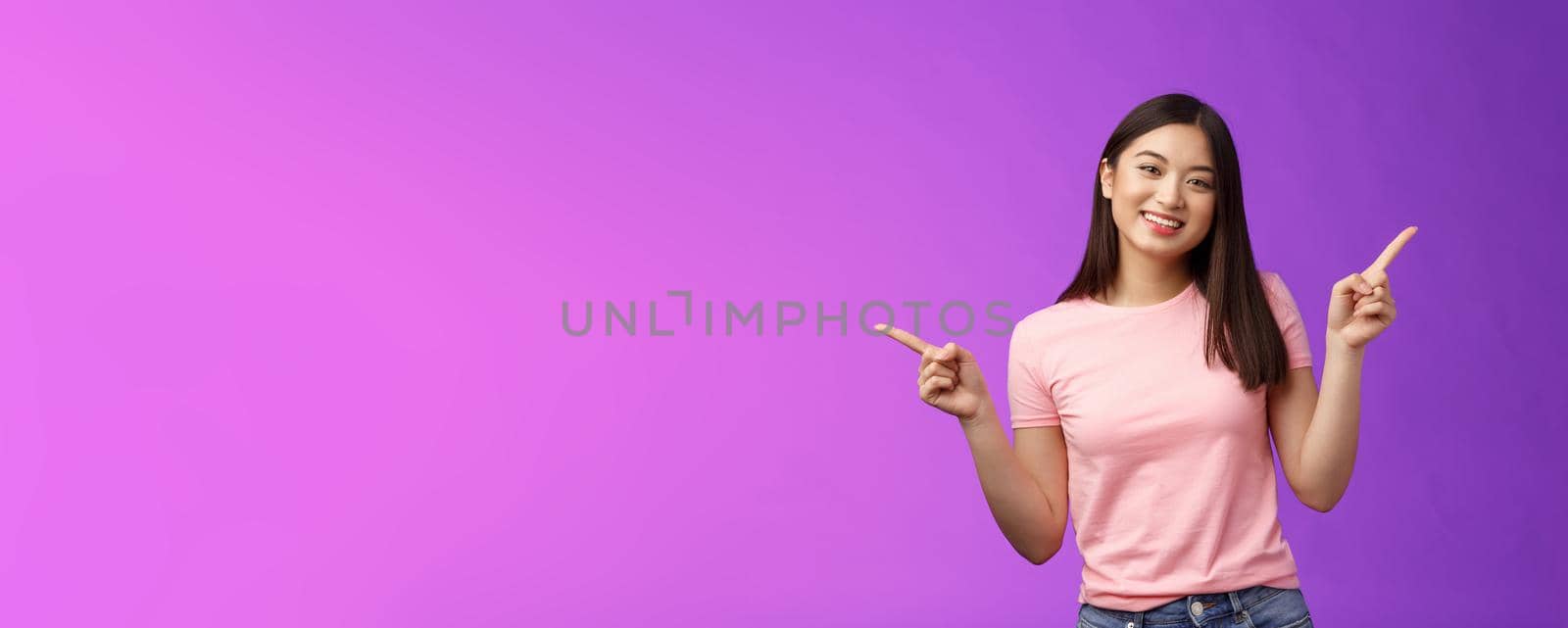 Charismatic relaxed cute asian woman short haircut pointing sideways introduce variety choices, showing left and right products, smiling joyfully, easily making decision, stand purple background.