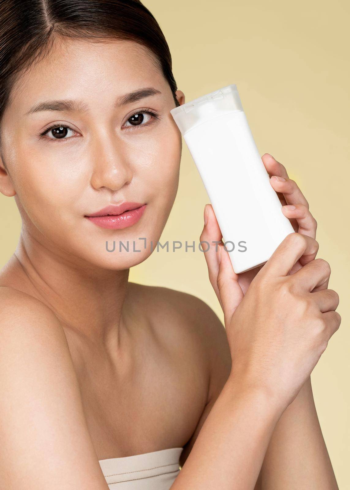 Closeup ardent woman smiling holding mockup product for advertising text place, light grey background. Concept of healthcare for skin, beauty care product for advertising.