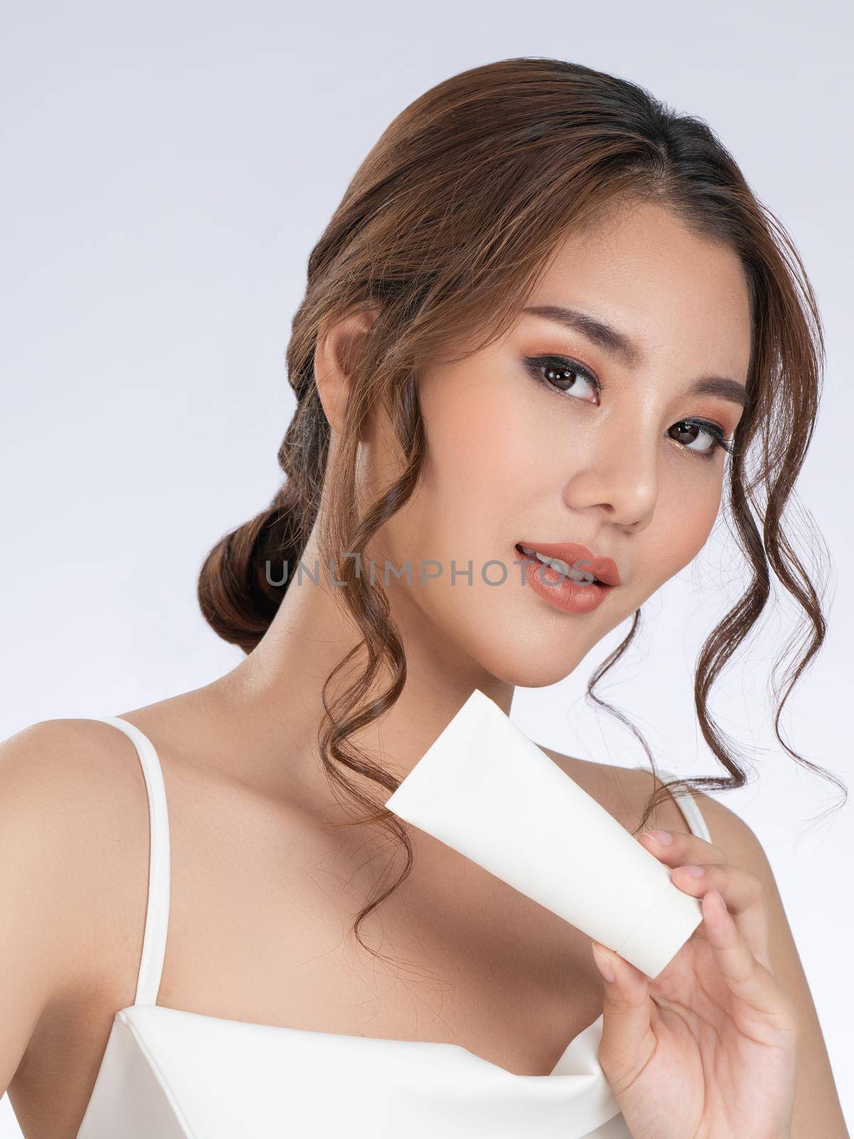 Gorgeous woman with makeup smiling holding mockup product for advertising. by biancoblue