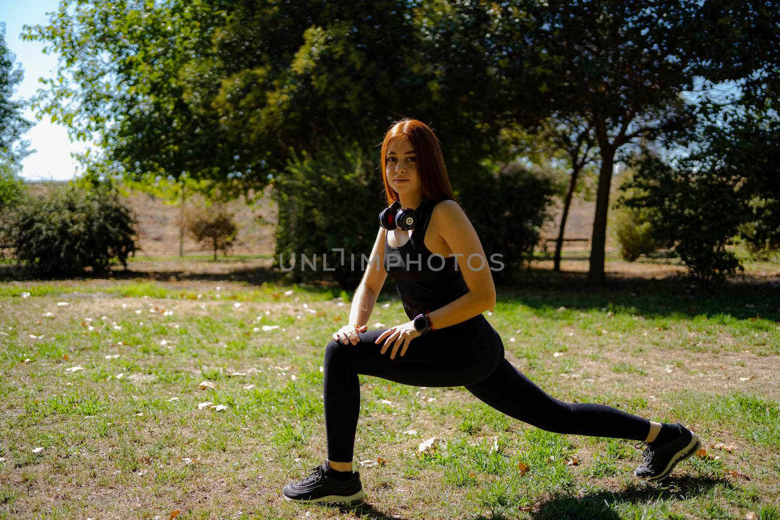 Redhead fitness woman doing lunge exercises for leg muscle training. by barcielaphoto