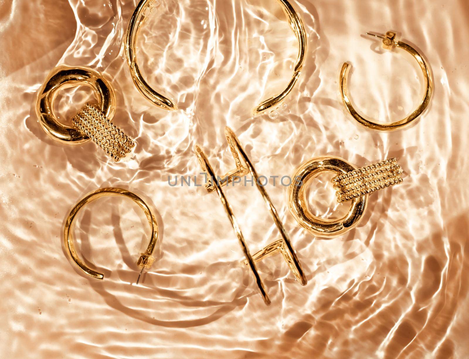 Jewellery branding, fashion gift and luxe shopping concept - Golden bracelets, earrings, rings, jewelery on gold water background, luxury glamour and holiday beauty design for jewelry brand ads