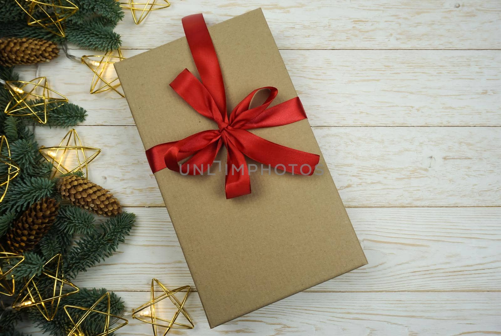 On a wooden table there is a gift in craft paper with a red bow . High quality photo