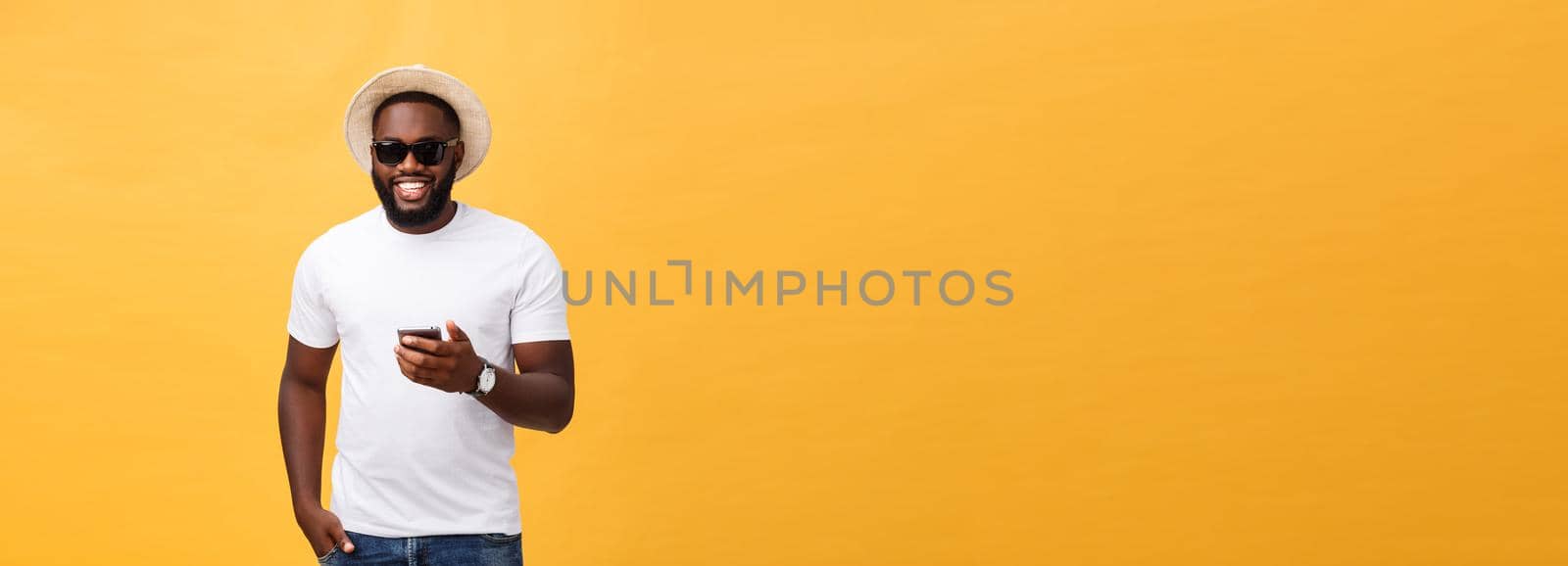 Cheerful African American man in white shirt using mobile phone application. happy dark skinned hipster guy read news from social network in mobile phone. by Benzoix