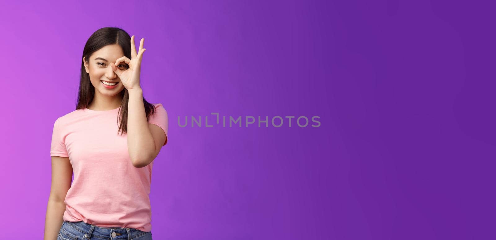 friendly cheerful young asian lady enjoy perfect summer day, show okay ok sign on eye, look through finger-circle, stand purple background joyful, recommend good place, feel excellent.