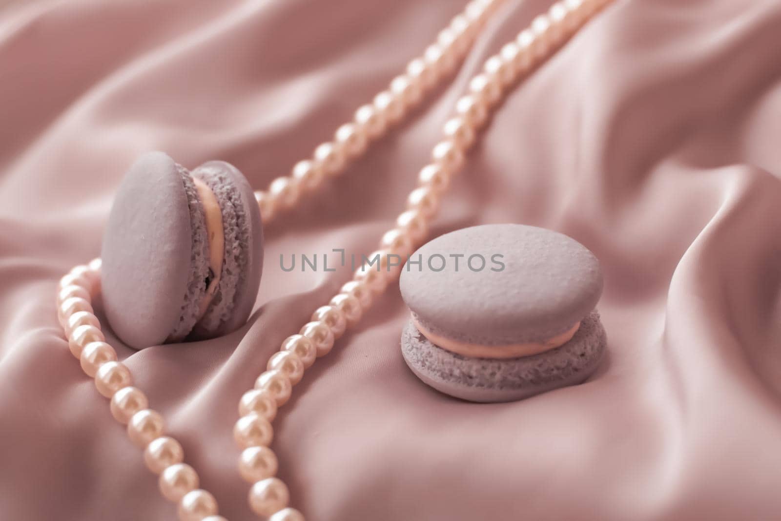 Girly, bakery and branding concept - Sweet macaroons and pearls jewellery on silk background, parisian chic jewelry, French dessert food and cake macaron for luxury confectionery brand, holiday gift