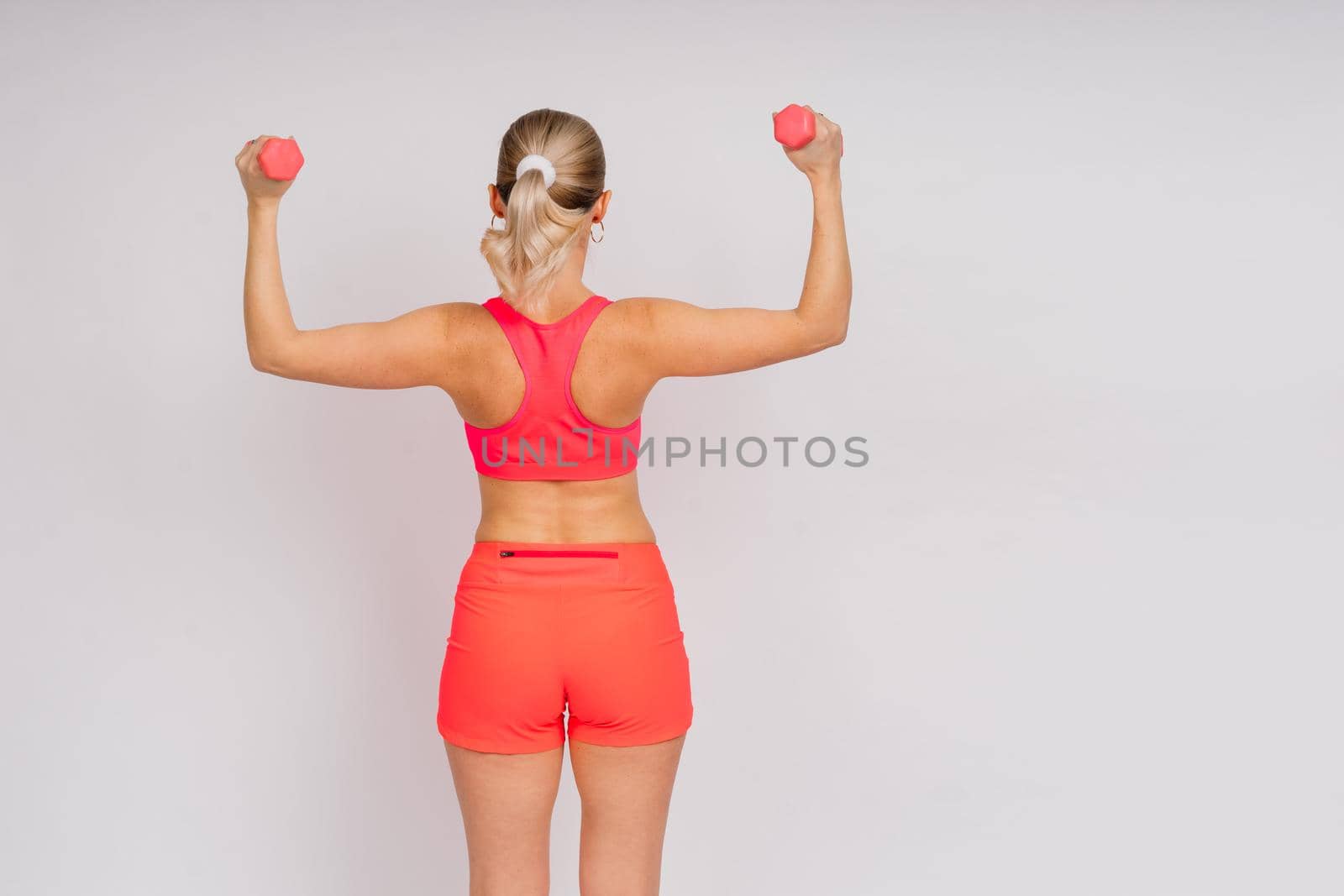 Full length portrait of smiling young woman in sportswear isolated over studio background. by Zelenin