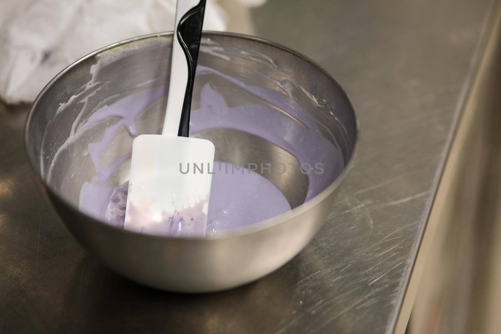 chef making for icing a lilac drip cake in the professional kitchen lab