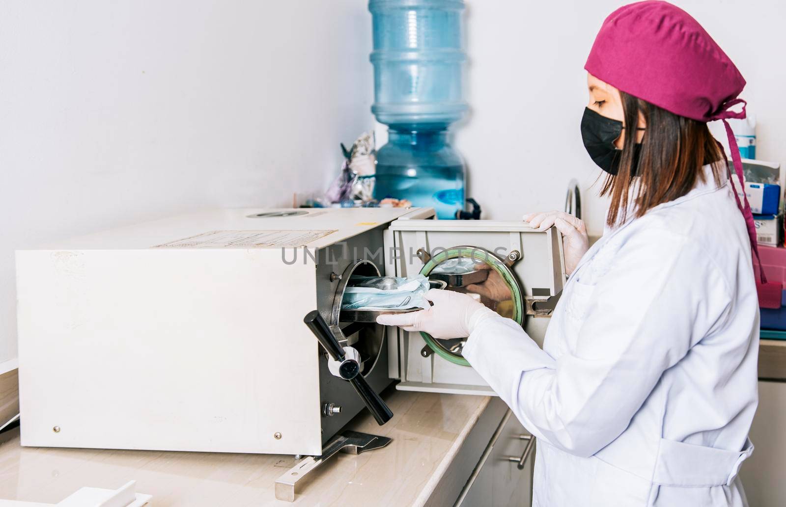 Hands of dentist sterilizing tools with autoclave, Dentist with dental autoclave, Closeup of dentist with steam sterilizer. Hands with dental sterilizer machine, Dentist with dental sterilizer