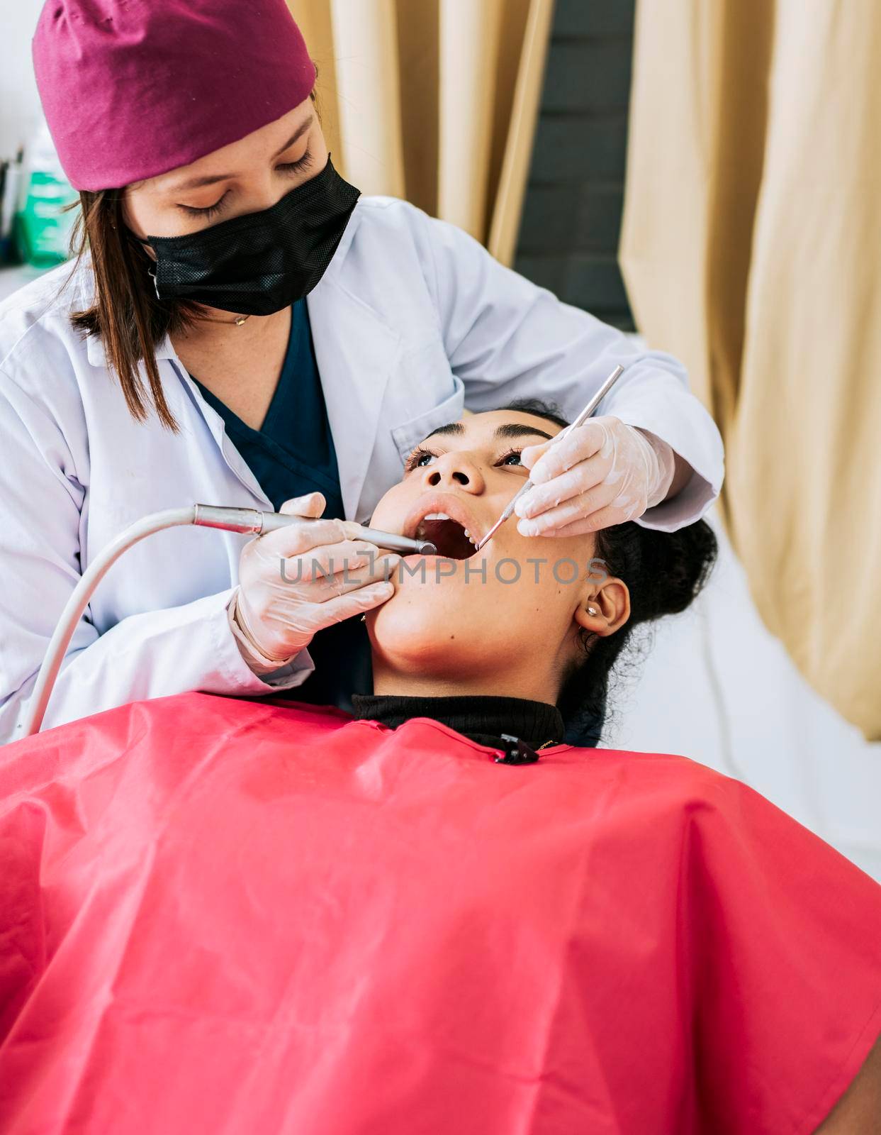 Professional dentist cleaning a female patient's mouth, Female dentist cleaning and examining a female patient mouth. Dental specialist cleaning the teeth of a female patient by isaiphoto