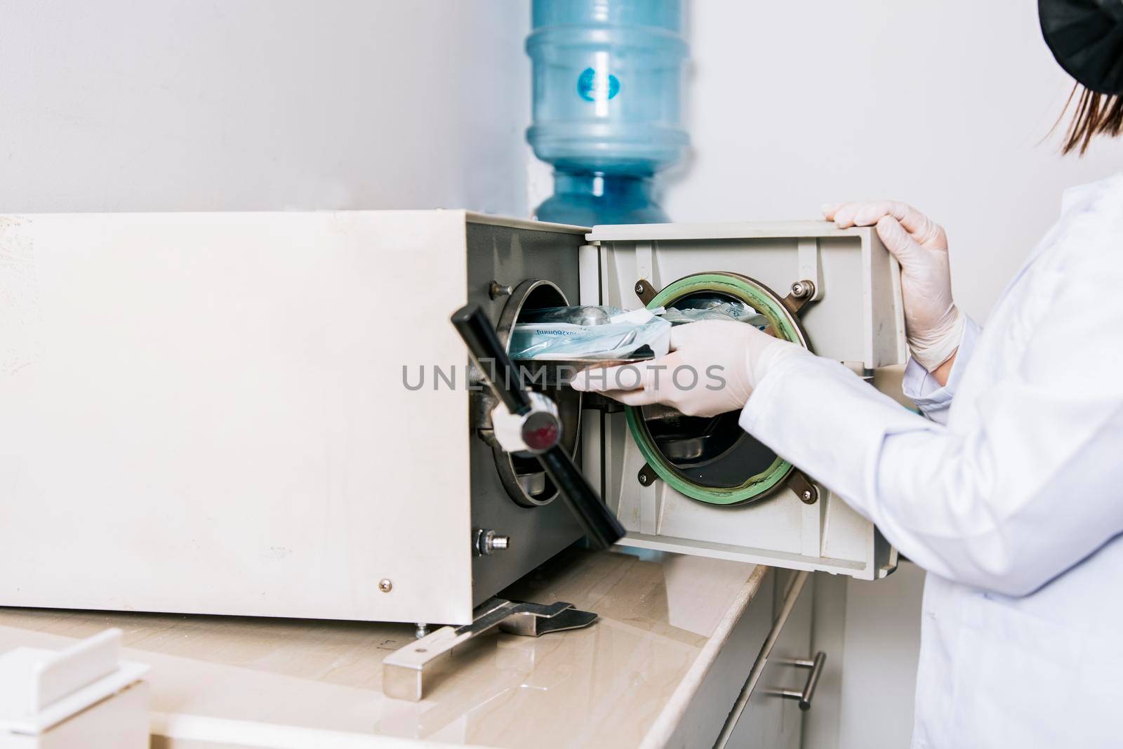 Dentist with dental sterilizer, Dentist hands sterilizing his tools, Dentist with dental autoclave, Close up of dentist with steam sterilizer. Hands with dental sterilizer machine