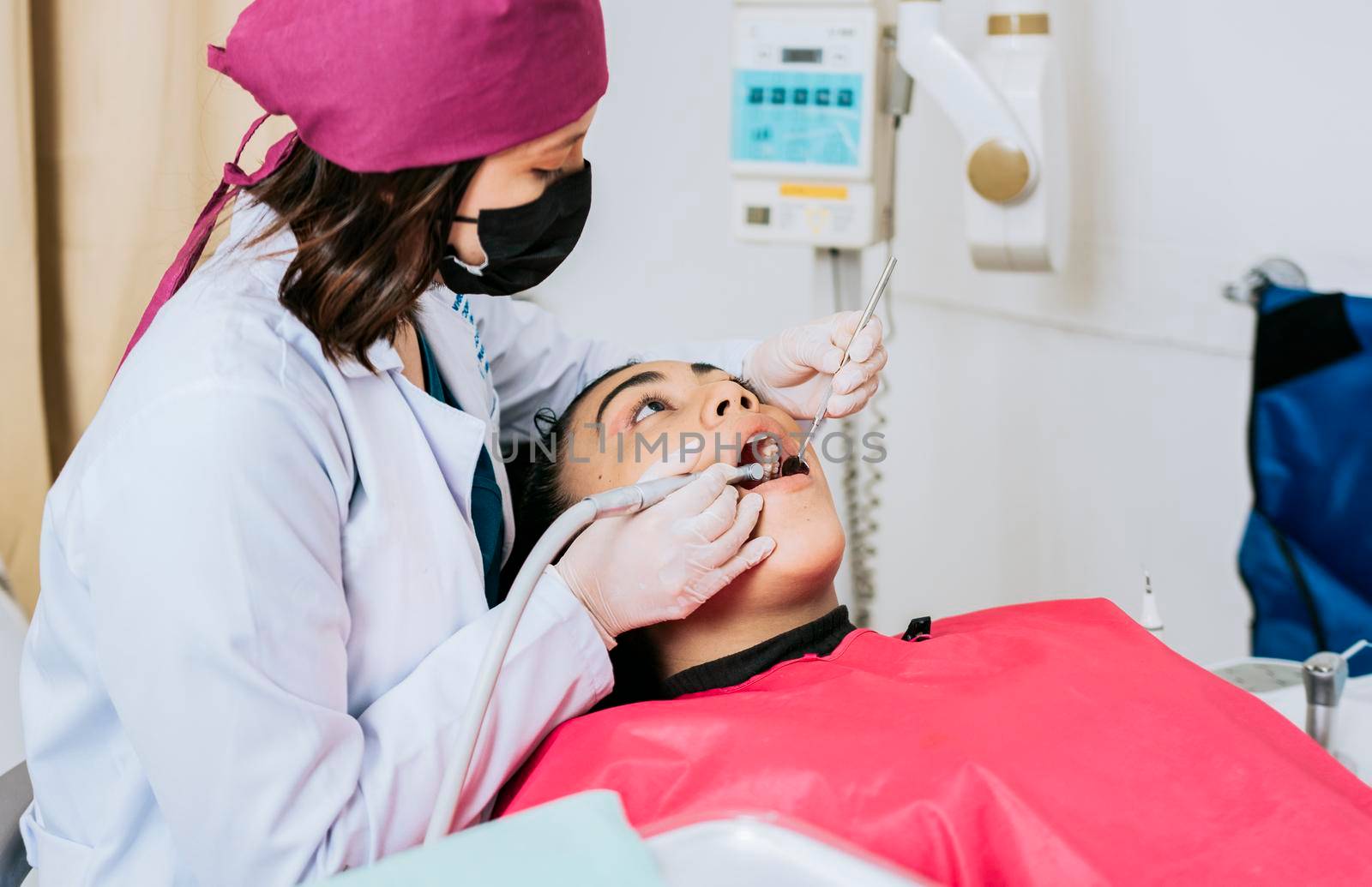 Dental specialist cleaning the teeth of a female patient. Professional dentist cleaning a female patient's mouth, Female dentist cleaning and examining a female patient's mouth