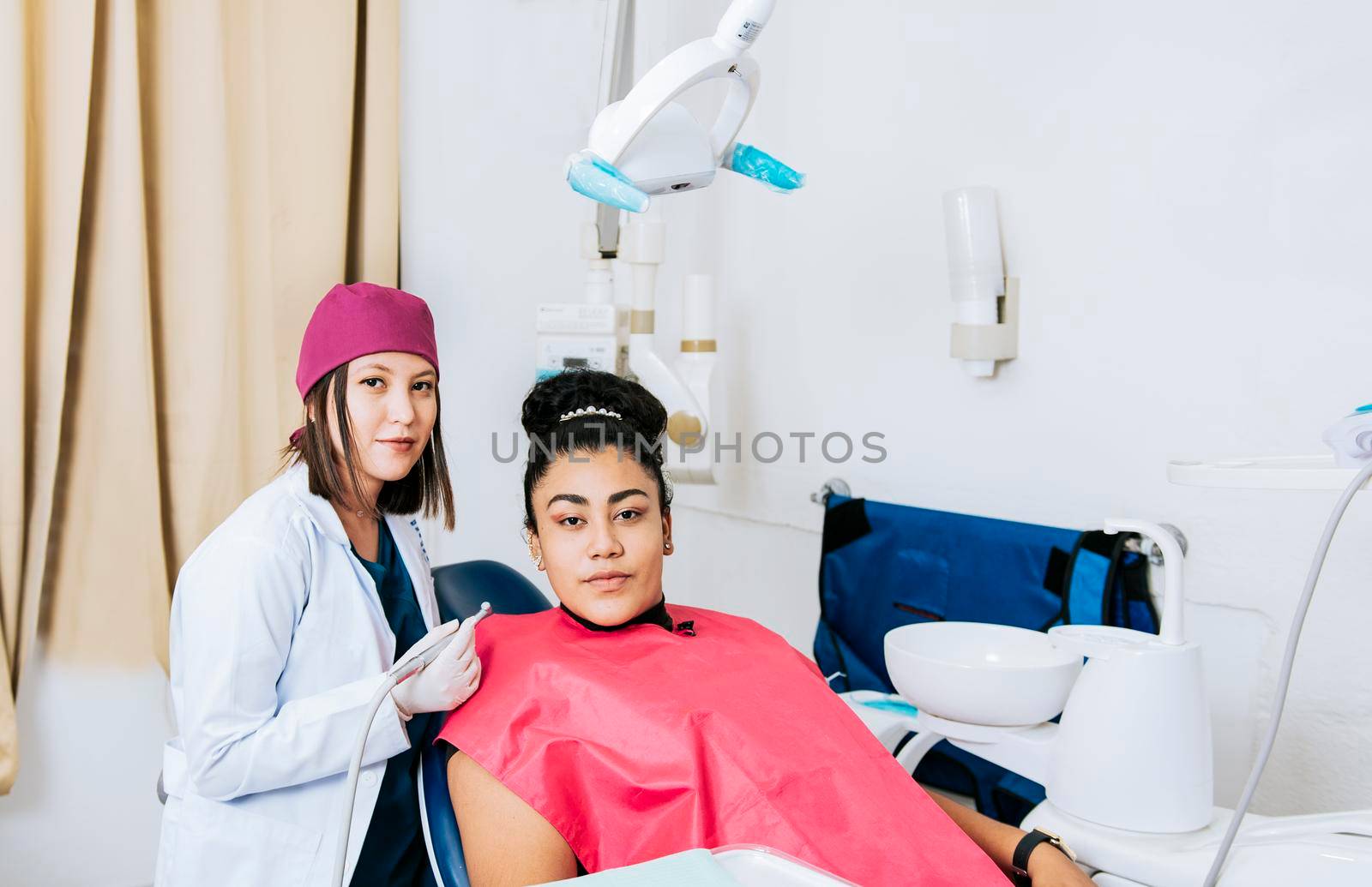 Portrait of young dentist with female patient in medical office, Female dentist with female patient looking at camera, Professional dentist with female patient in office.