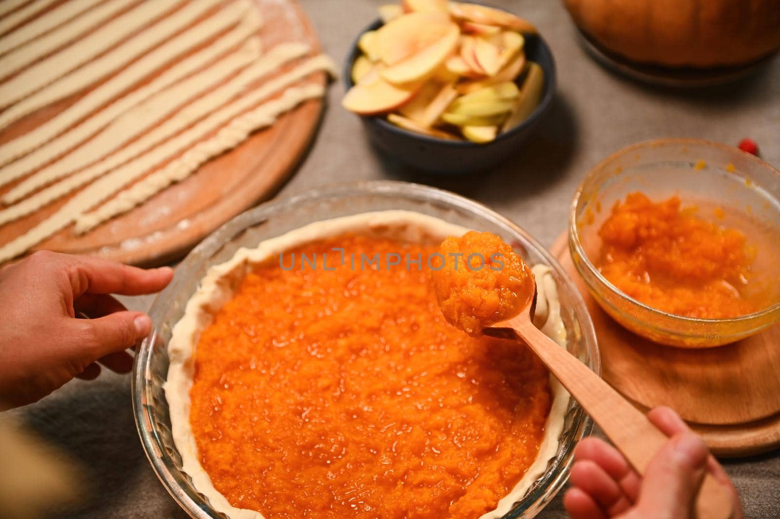 Close-up of a housewife holding a pumpkin puree spoon over a classic American Thanksgiving dinner pie. Food still life by artgf