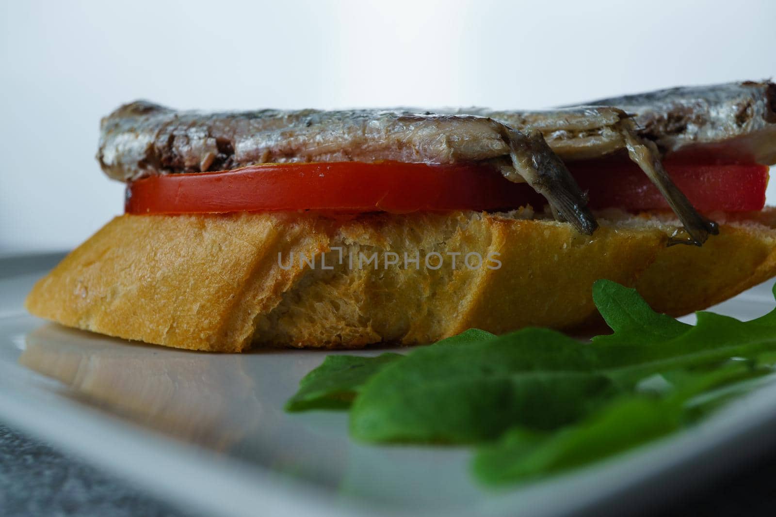 tapa of sardines with tomato and olives on a white plate with a typical spanish white background by joseantona