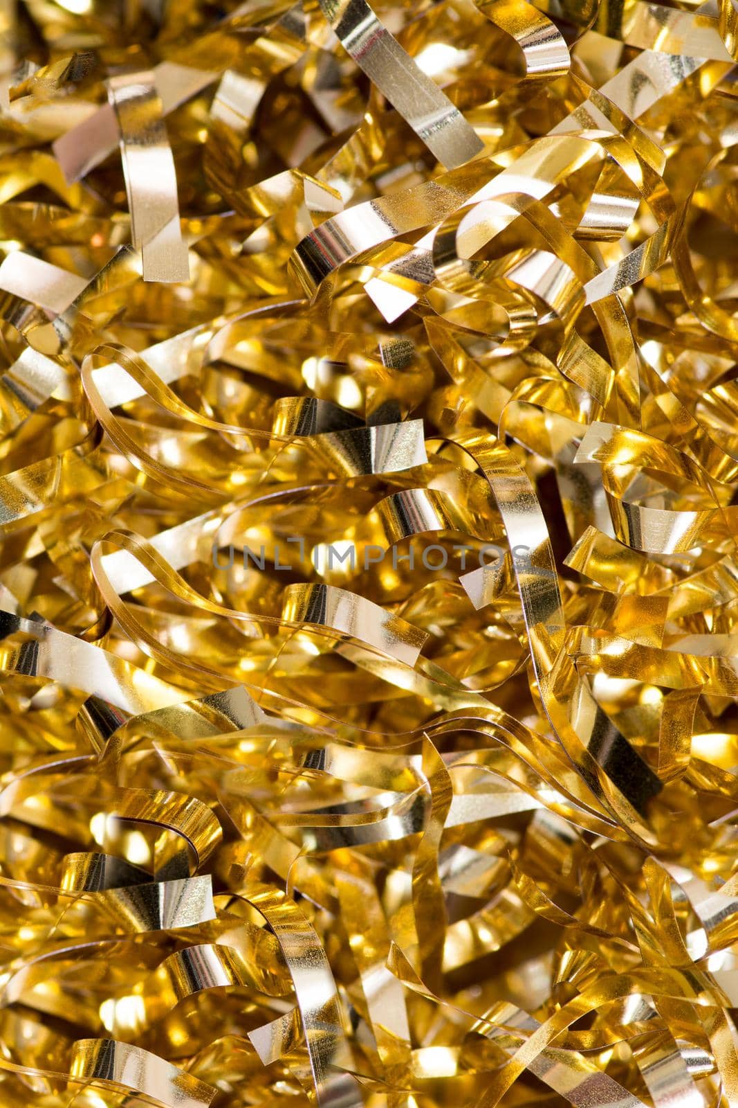 A small unfocused pile of laminated tinsel of golden color. Industrial waste . Selective focus.Texture or background